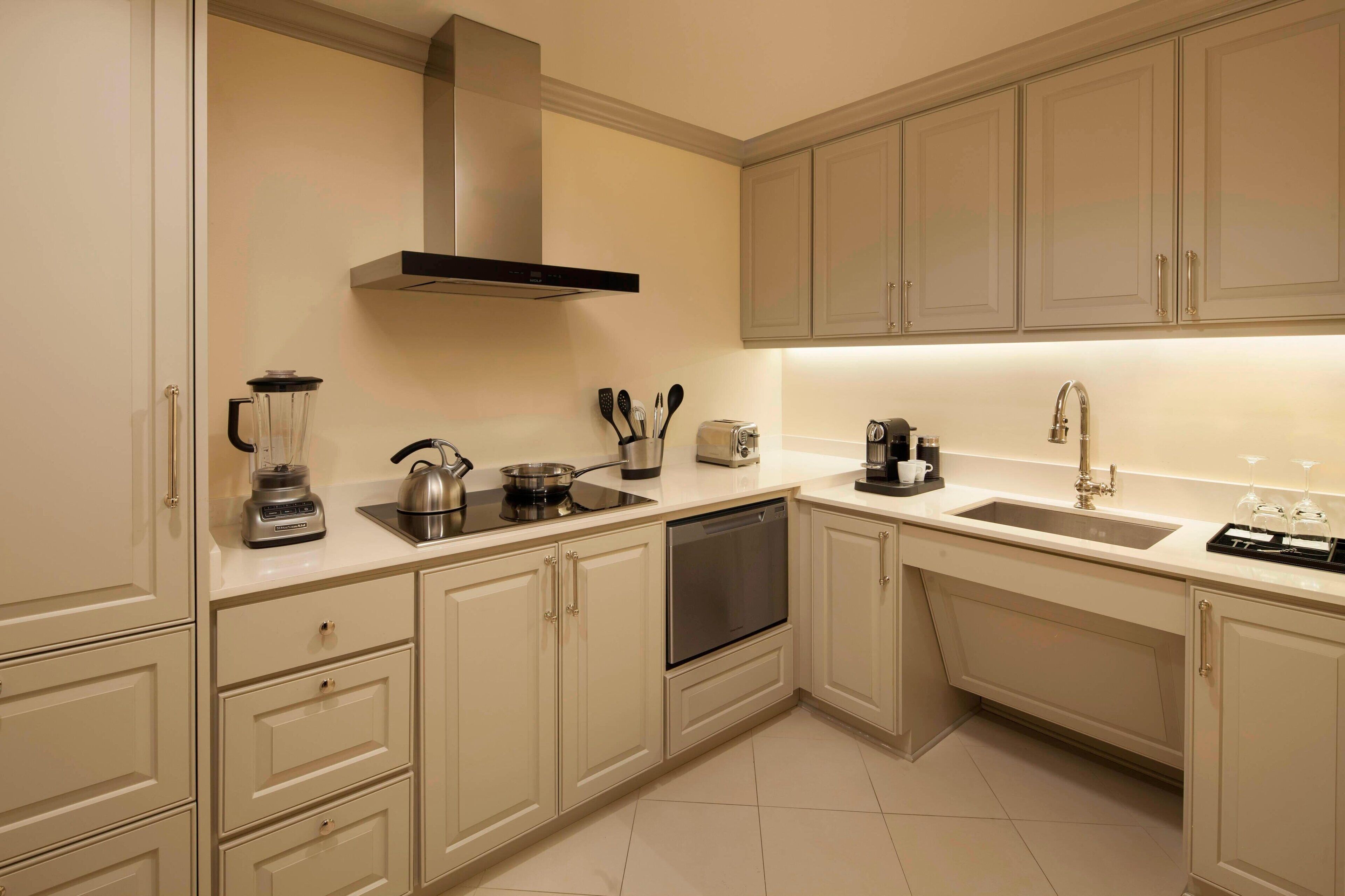 A modern kitchen with white cabinets, a built-in oven, a sink, and a stove.