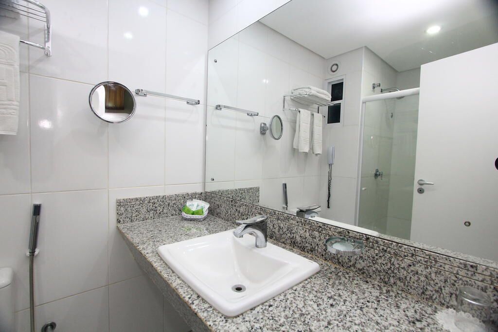 A modern bathroom with a white sink, granite countertop, and a large mirror.
