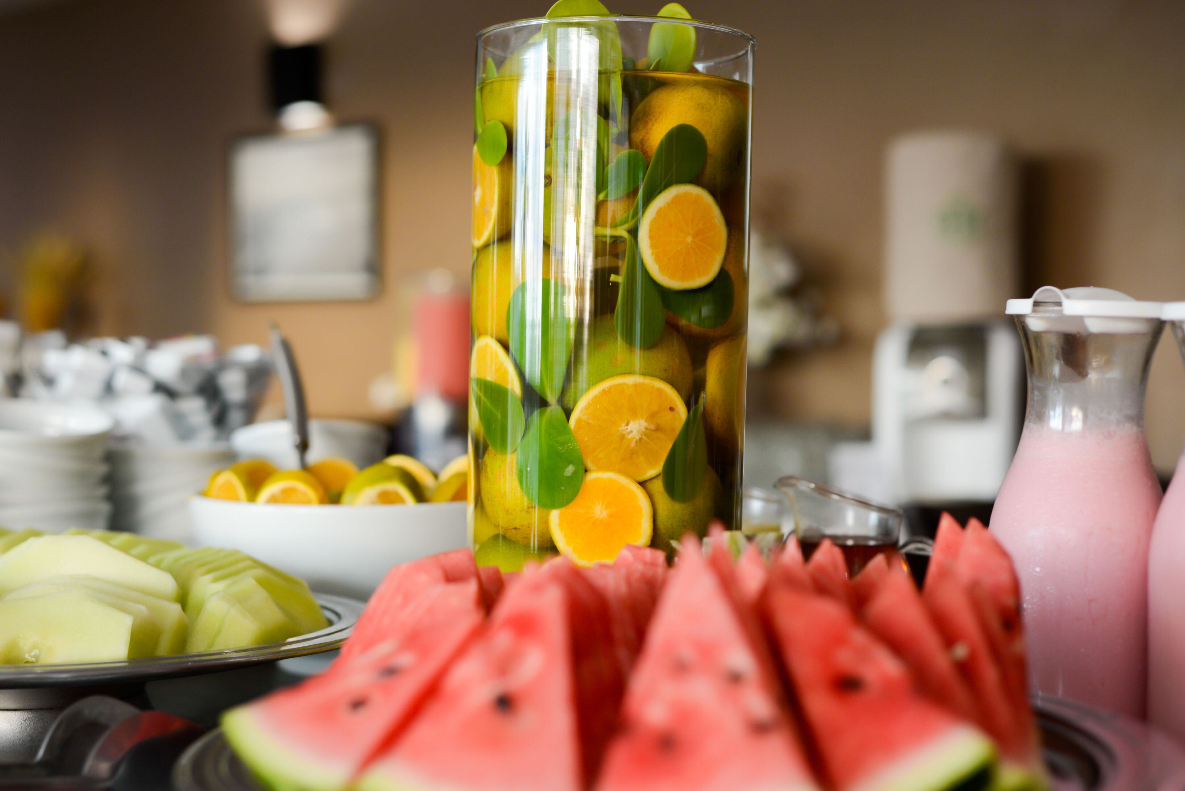 A glass filled with fruit slices and a bowl of sliced watermelon.
