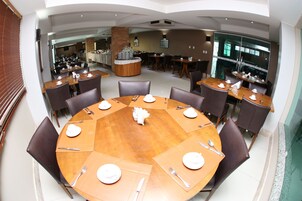 A spacious dining area with multiple round tables set for dining, surrounded by chairs.