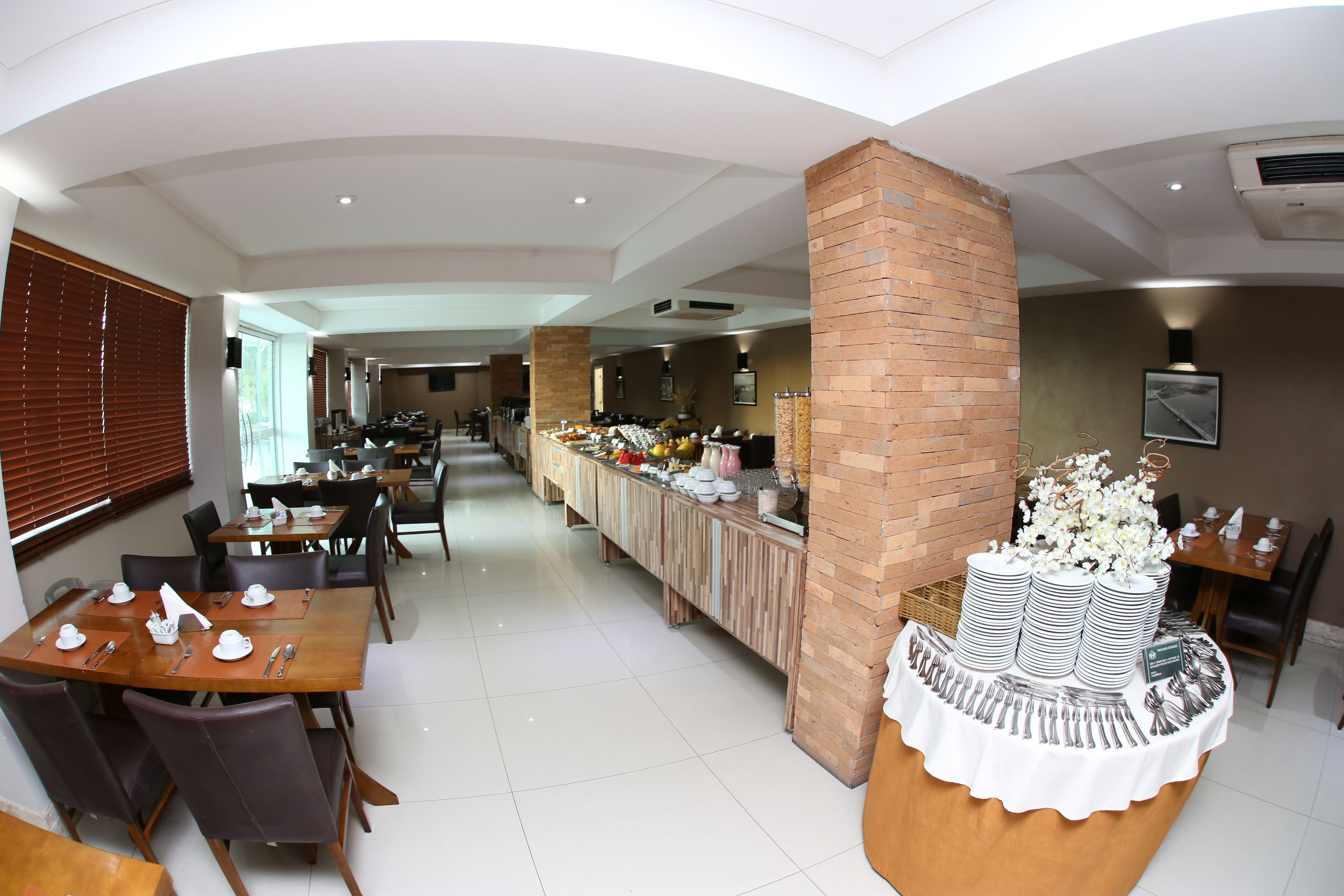 A spacious dining area with multiple tables and chairs, a buffet counter with various food items, and a brick pillar.