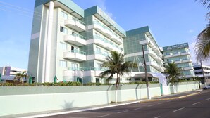 A multi-story hotel with balconies, a clear sky, and palm trees. - Real Classic Hotel (Aracaju)