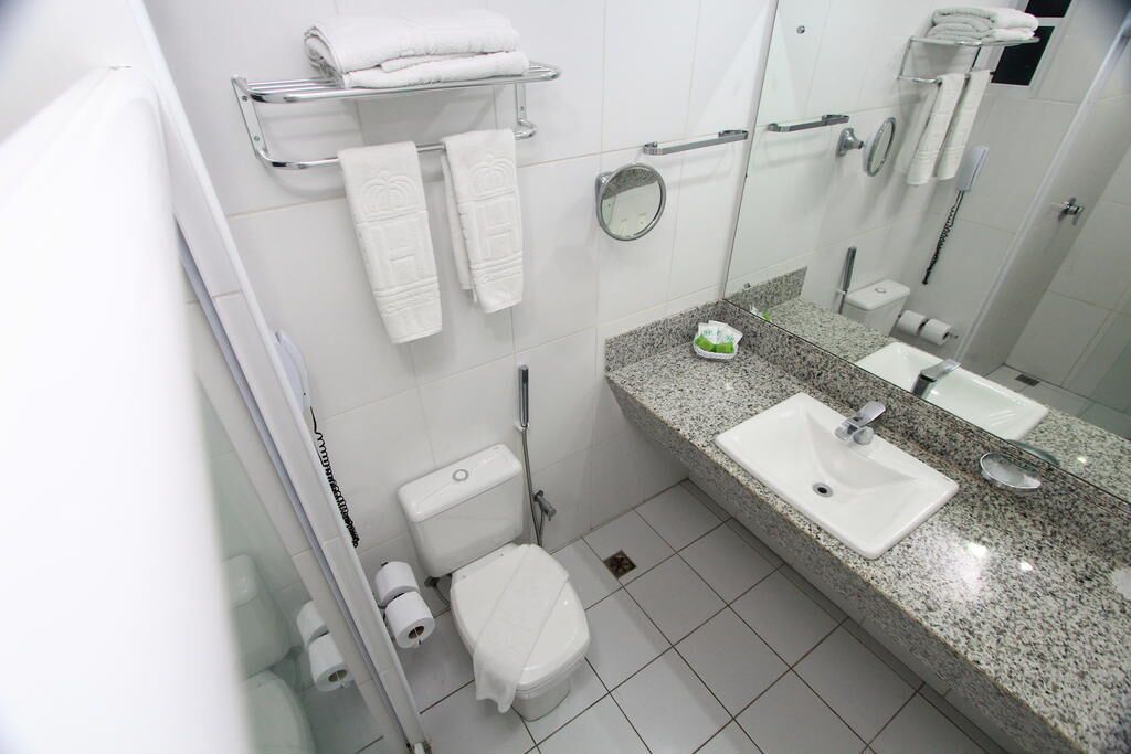 Un baño moderno con encimera de granito, dos lavamanos, inodoro y ducha.