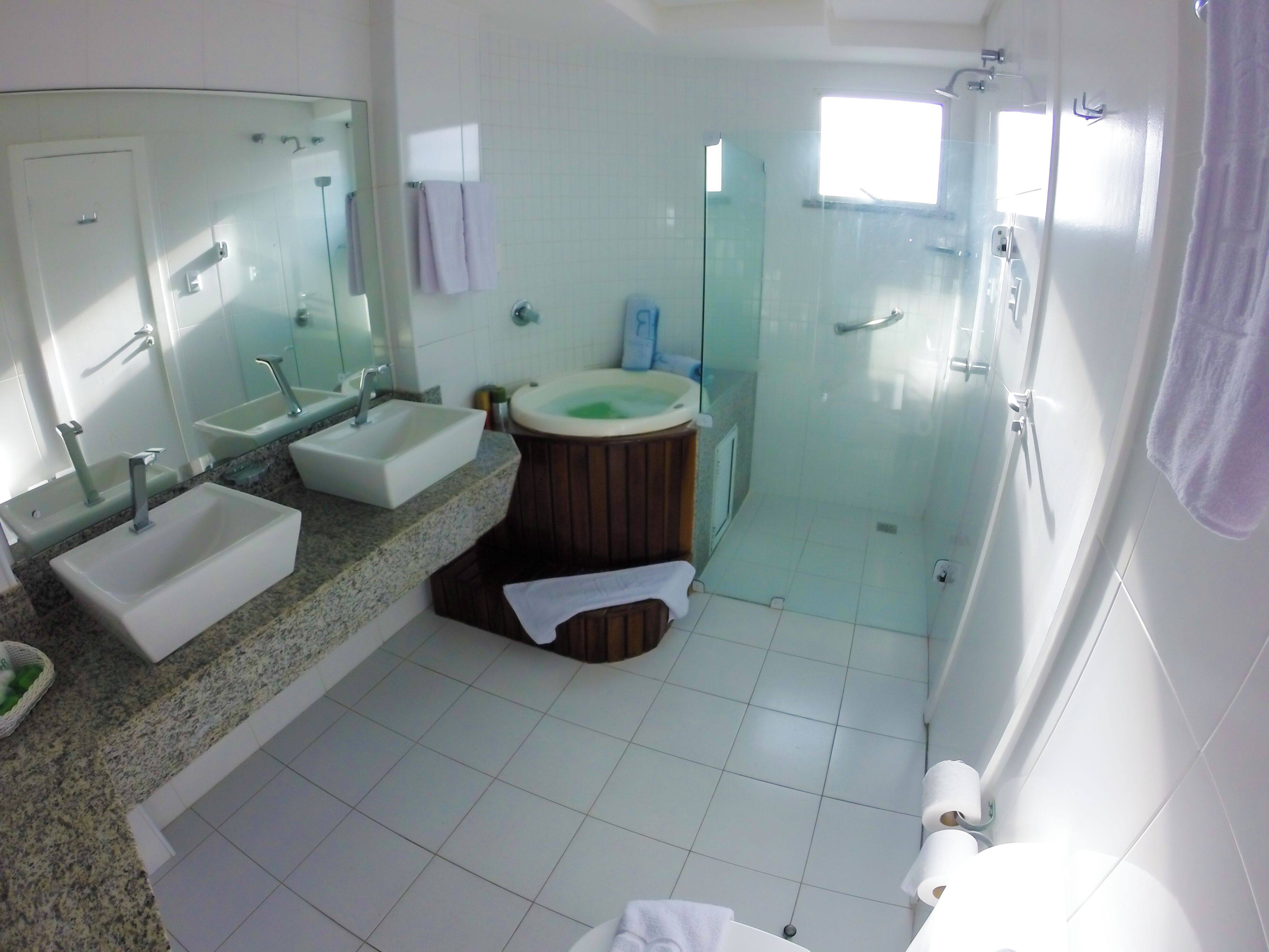 Casa de banho moderna com duas lavatórios, uma banheira, cabine de duche envidraçada e toucador com espelho.