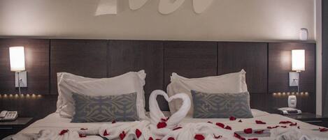 A hotel room with a large bed, two nightstands, and a wall with a large letter 'M'.