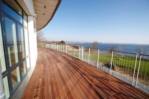Eine Holzterrasse mit Blick auf das Meer und eine entfernte Skyline.
