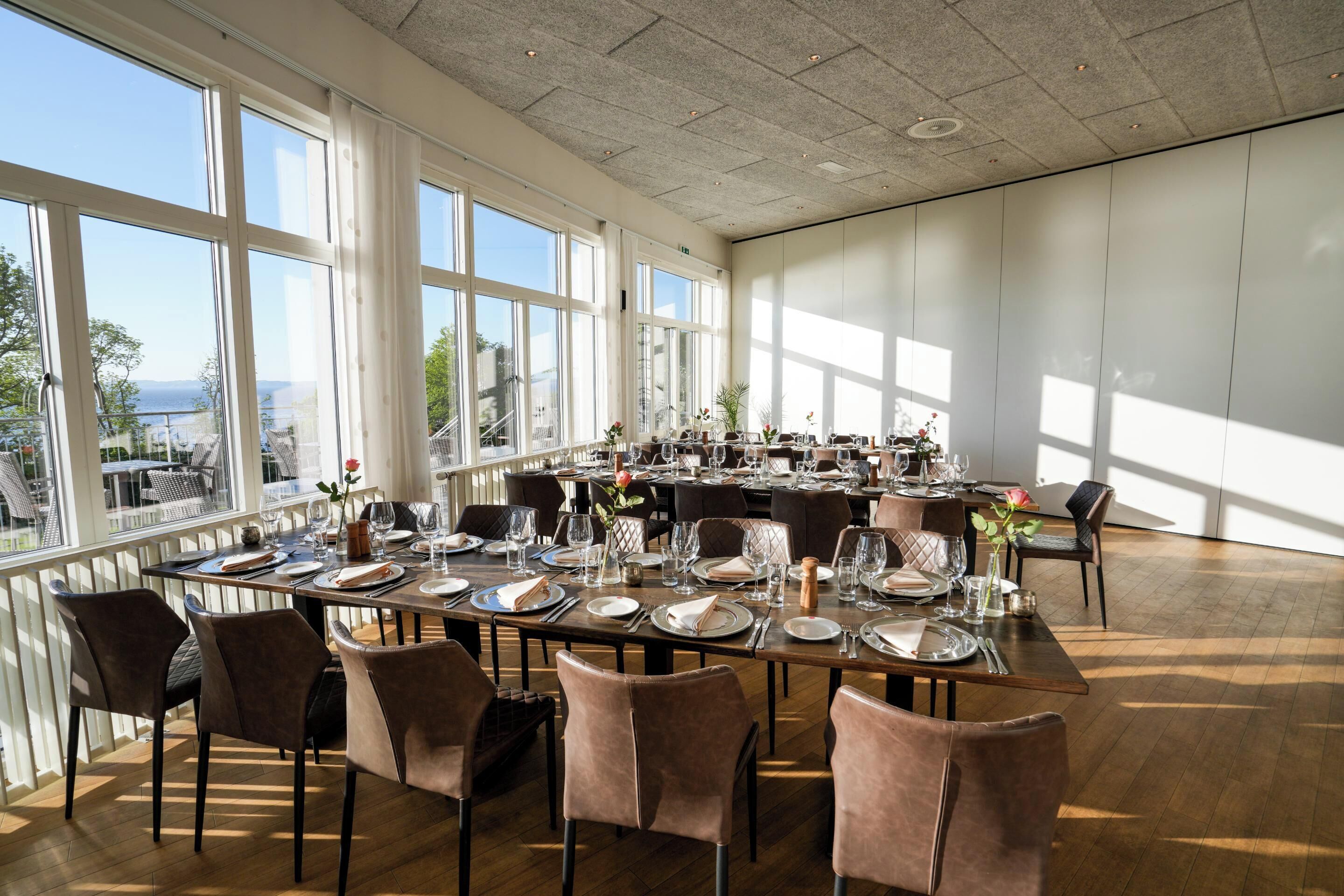 Un comedor amplio con ventanas grandes, mesas de madera y sillas modernas.