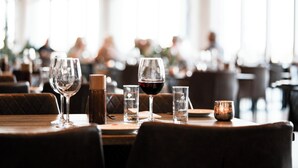 Une salle de restaurant avec des tables, des verres à vin et une bougie.