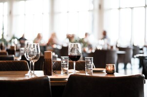 En restaurantscene med borde, vinglas og et stearinlys.