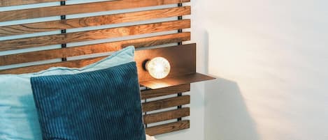 A bed with a wooden headboard, a bedside lamp, and a pillow.
