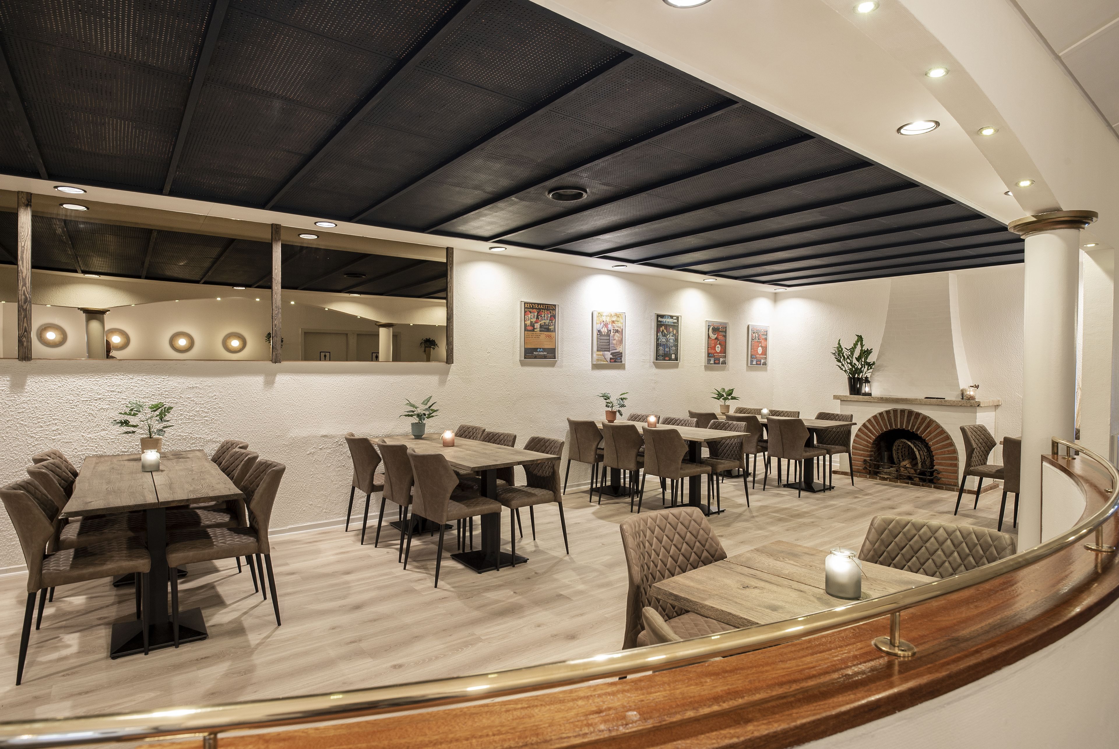 Un vaste espace dédié à la salle à manger, avec plusieurs tables et chaises, une cheminée et un design moderne au niveau du plafond.