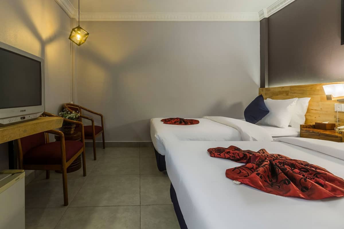 Une chambre d’hôtel équipée d’une télévision, d’un bureau, de deux lits, d’une chaise et d’une table de chevet.
