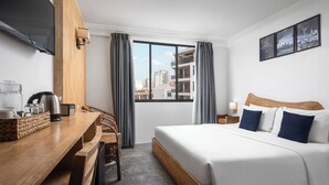 A hotel room with a bed, a desk, a chair, a television, and a window with curtains. - Pacific Hotel, Phnom Penh (Phnom Penh)
