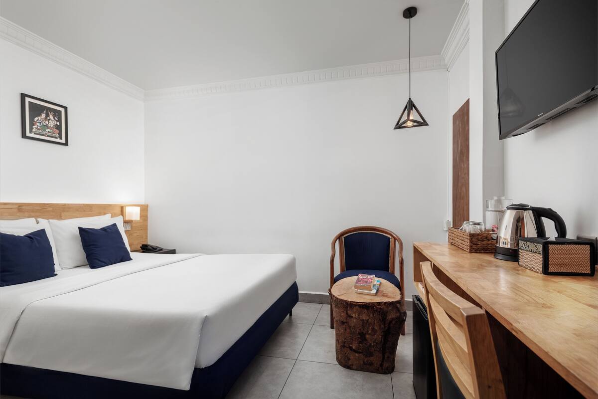 Une chambre d’hôtel équipée d’un lit, d’une chaise, d’une petite table, d’un téléviseur et d’une machine à café.