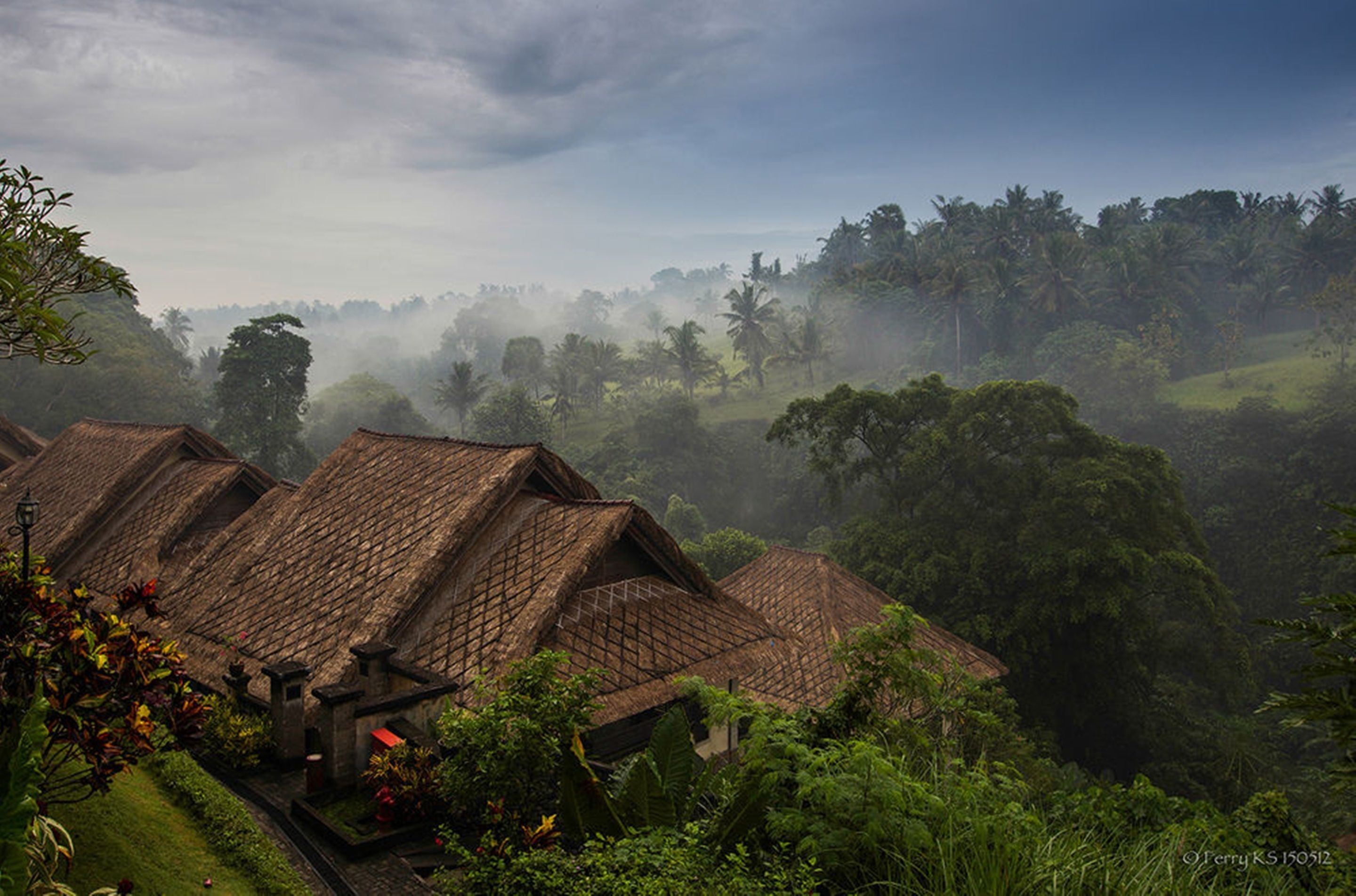 A traditional village with thatched-roof houses nestled in a lush, green valley.