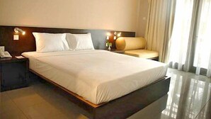 Ein Hotelzimmer mit einem großen Bett, einem Nachttisch, einer Couch und einem Fenster mit Vorhängen.