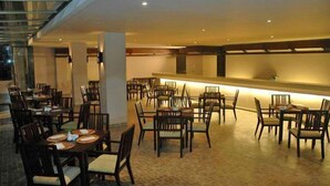 A spacious dining area with multiple tables and chairs, a long counter, and a high ceiling with recessed lighting. - The Pade Hotel (Banda Aceh)