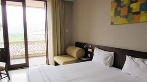 Ein Hotelzimmer mit Bett, Sessel, Nachttisch und Blick ins Freie.