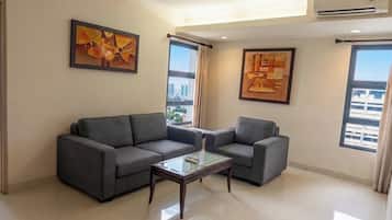 A modern living room with a grey sectional sofa, a glass coffee table, and two framed abstract paintings.
