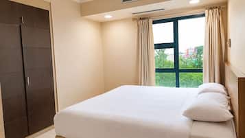 A bedroom with a bed, a wardrobe, and a window with curtains.