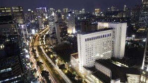 Een hoog hotel met meerdere verdiepingen, gelegen in een levendige stedelijke omgeving met zichtbare straten en andere gebouwen.