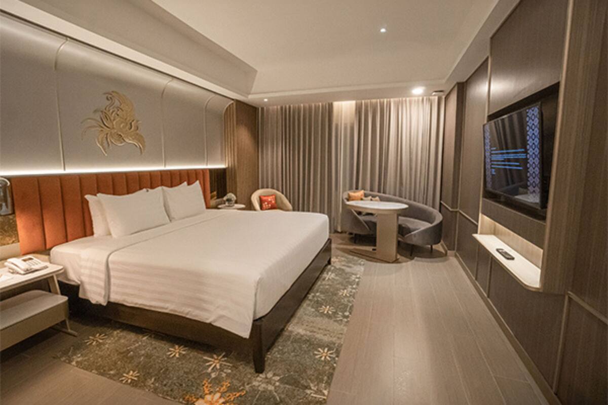 Une chambre d’hôtel moderne dotée d’un grand lit, d’un bureau, d’une chaise, d’un téléviseur et d’une paroi vitrée.