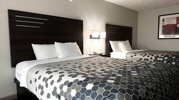 A hotel room with two beds, a modern headboard, a wall-mounted phone, and a framed abstract painting.