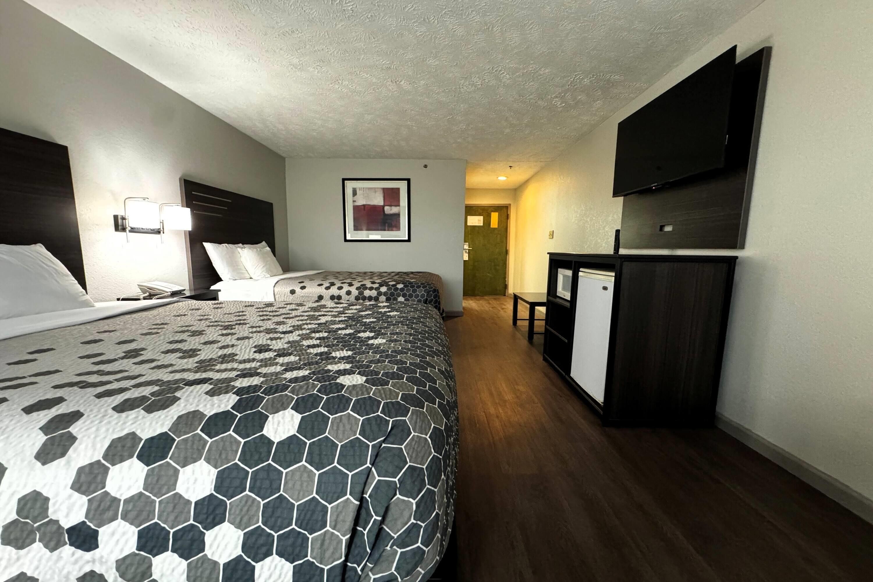 Une chambre d’hôtel avec un grand lit, un bureau, un téléviseur à écran plat et un tableau encadré au mur.