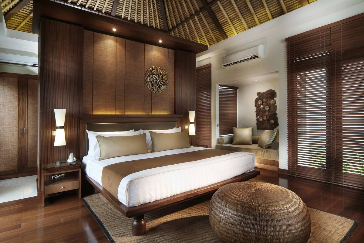 A spacious bedroom with a large bed, wooden headboard, and a decorative wall piece.