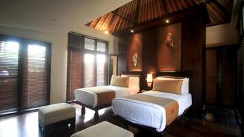 A hotel room with two beds, a large window with blinds, a wooden ceiling, and a small table.