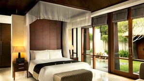 Ein geräumiges Schlafzimmer mit einem großen Bett, einem Nachttisch mit Lampe, einer Bank und Blick auf Pool und Garten durch große Fenster.
