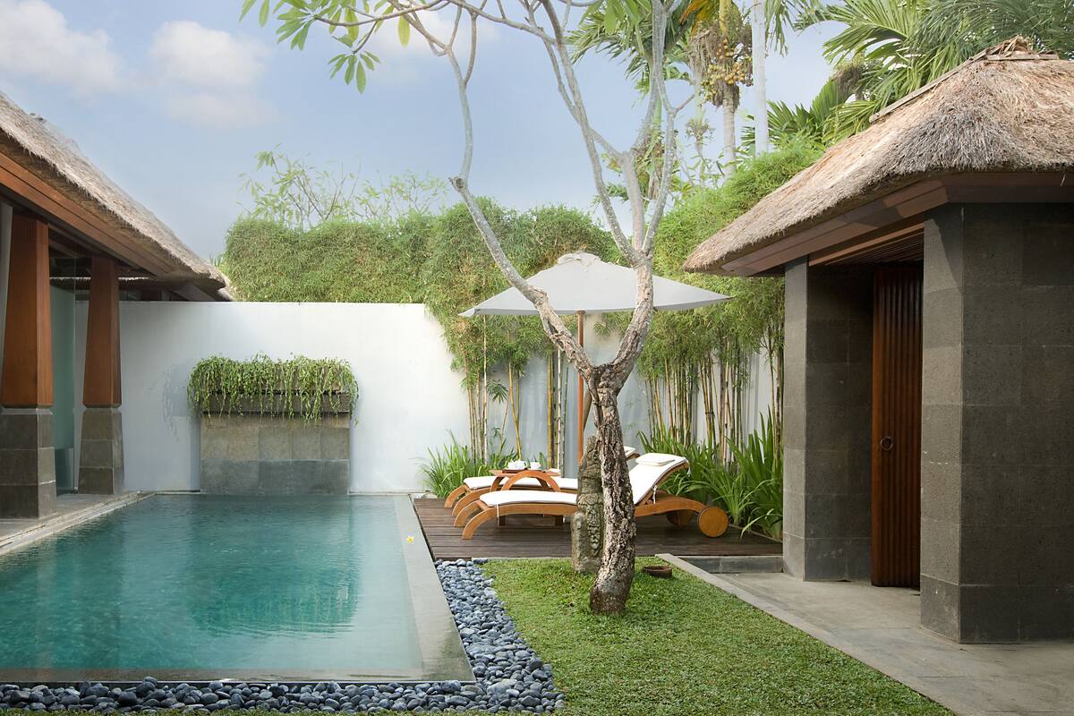 A modern pool area with a clear pool, wooden deck, and lounge chairs.