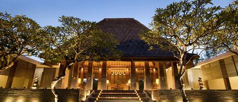 A building with a large entrance, steps leading up to it, and trees in front.