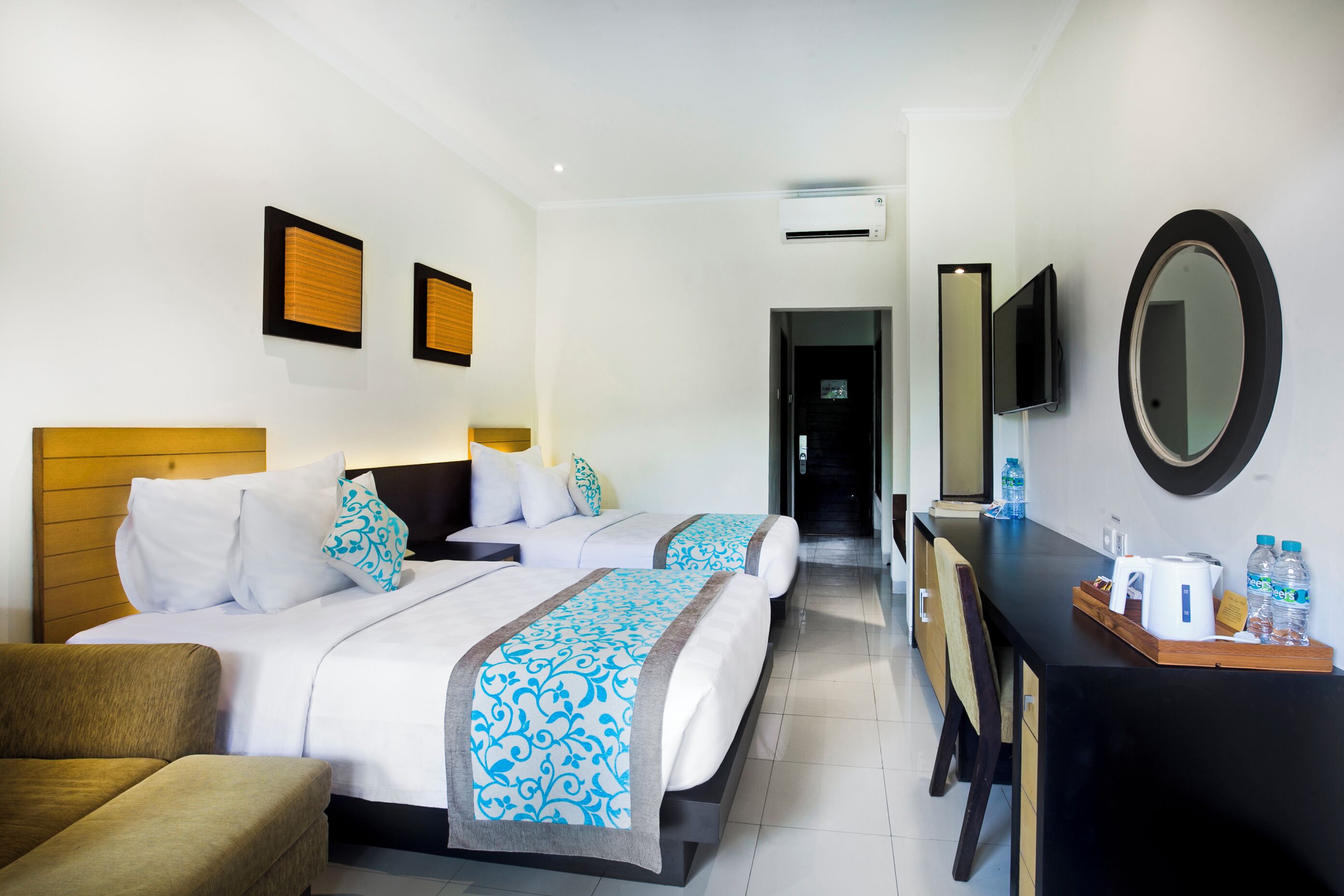 A hotel room with two beds, a desk, a chair, a TV, and a mirror.