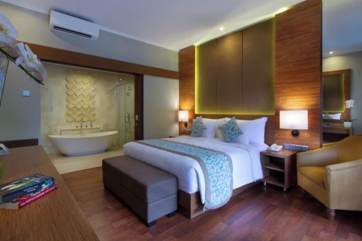 Ein Hotelzimmer mit einem großen Bett, einer Badewanne, einem Schreibtisch und einem Sessel.