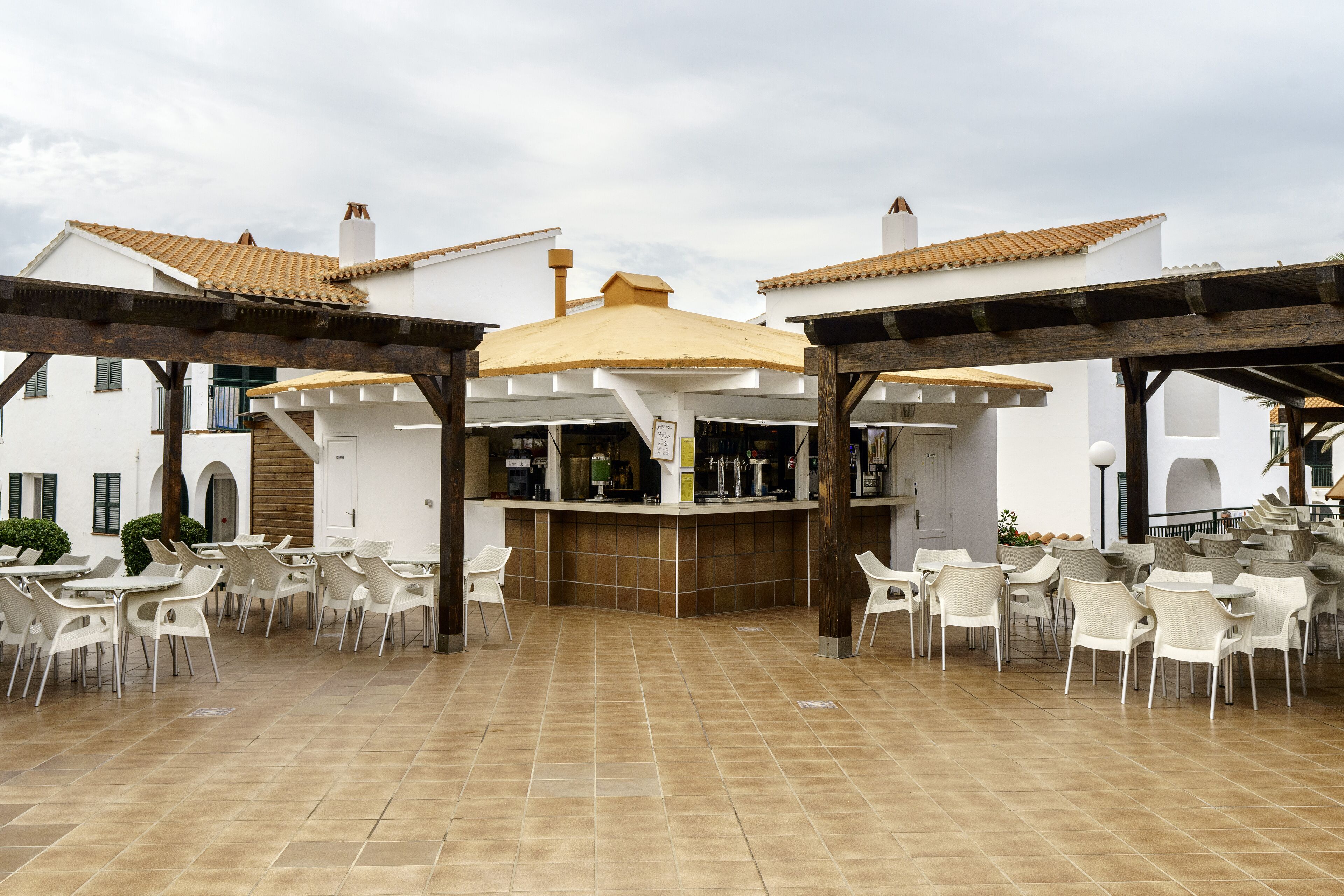 An outdoor patio area with white chairs and a bar counter.