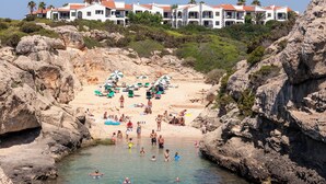 Um hotel à beira-mar com vários edifícios brancos, uma praia rochosa e águas cristalinas.