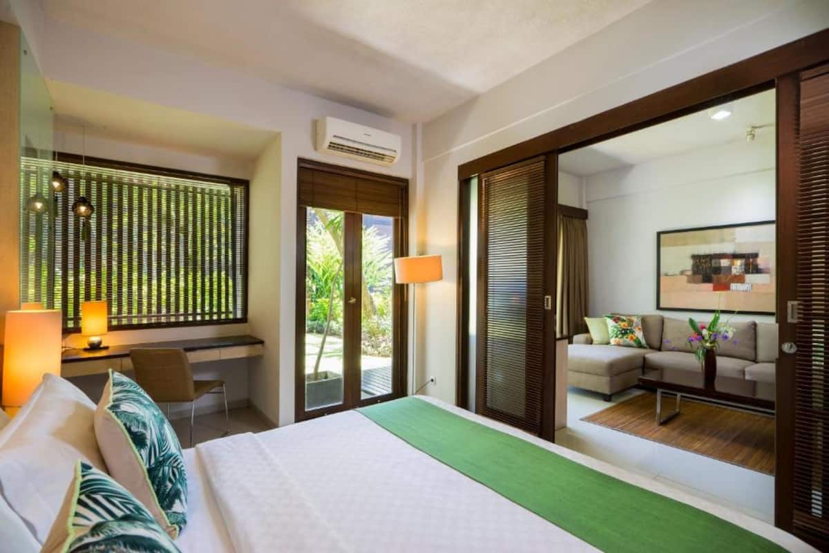 Ein Hotelzimmer mit Bett, Schreibtisch, Sessel, Sofa und einem großen Spiegel.