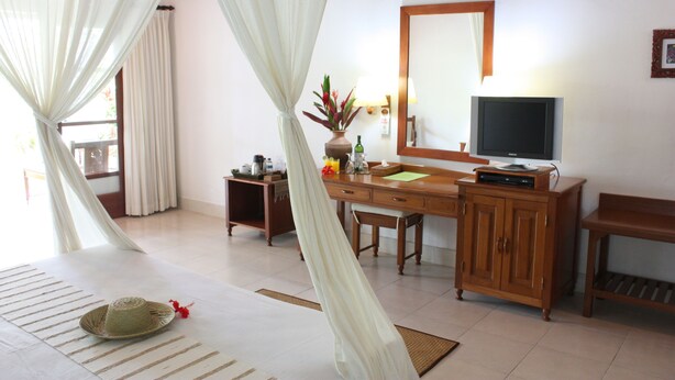 A hotel room with a bed, a desk, a television, and a cabinet. - Bumi Ayu Bungalows (Denpasar)