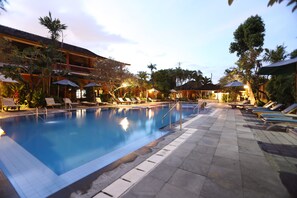 Una piscina al aire libre, sombrillas, sillones reclinables de piscina