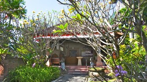 Un edificio tradicional con entrada al jardín, una fuente y una estatua.