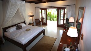 Un dormitorio con cama, mesita de noche, lámpara y vistas al exterior.