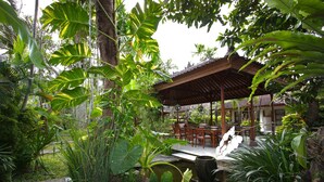 Un exuberante jardín con un estanque, una pérgola de madera y una zona de estar.