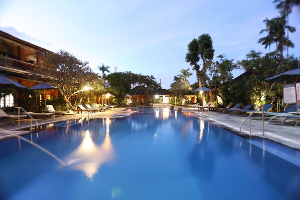 Una piscina al aire libre, sombrillas, sillones reclinables de piscina