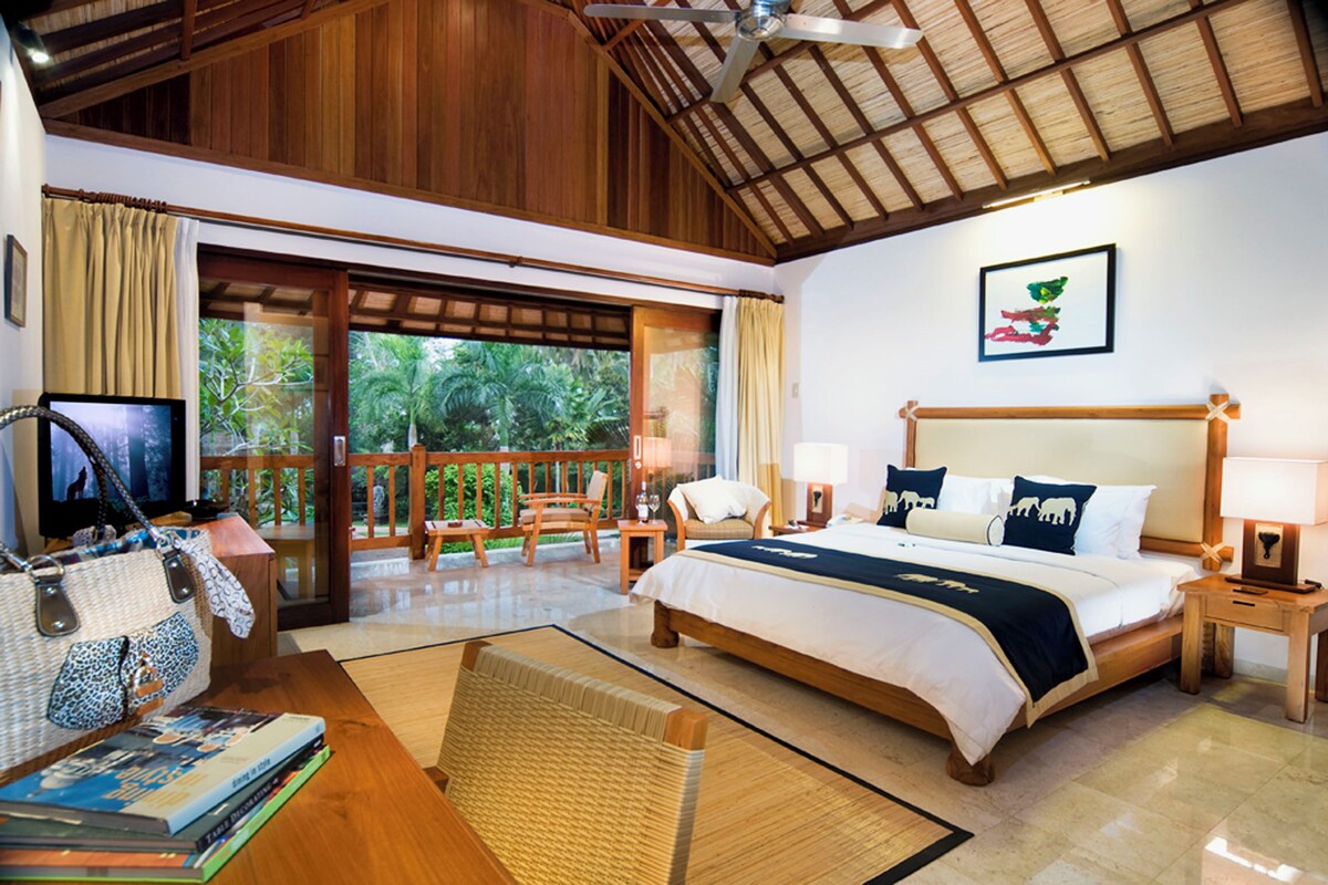 Habitación de hotel con una cama grande, un escritorio con computadora, una silla y vistas al exterior.