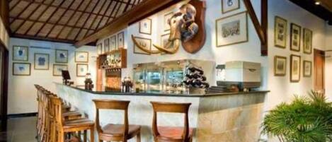 A bar area with wooden chairs, a marble counter, and framed pictures on the wall.