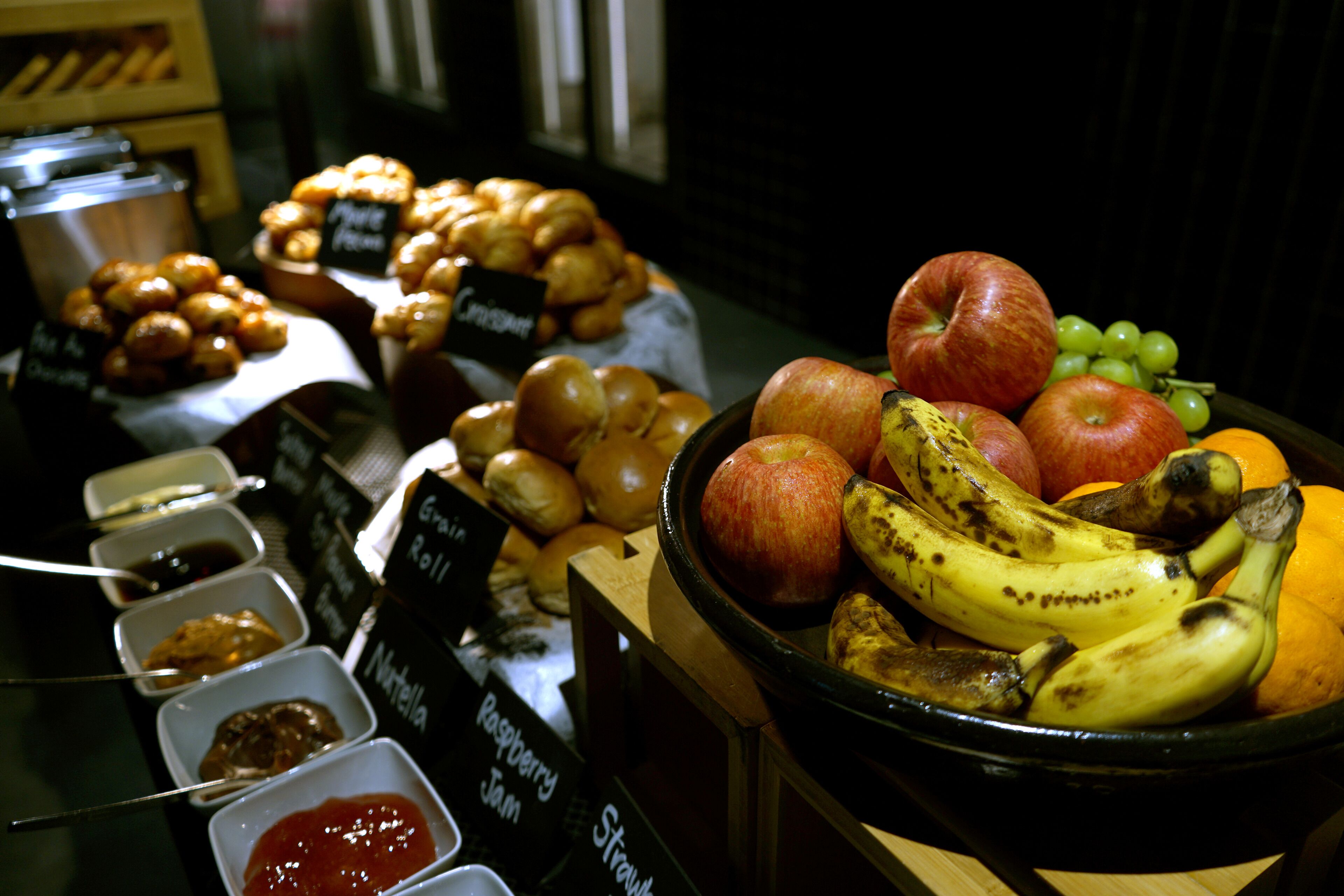 A breakfast buffet with various pastries, fruits, and condiments.