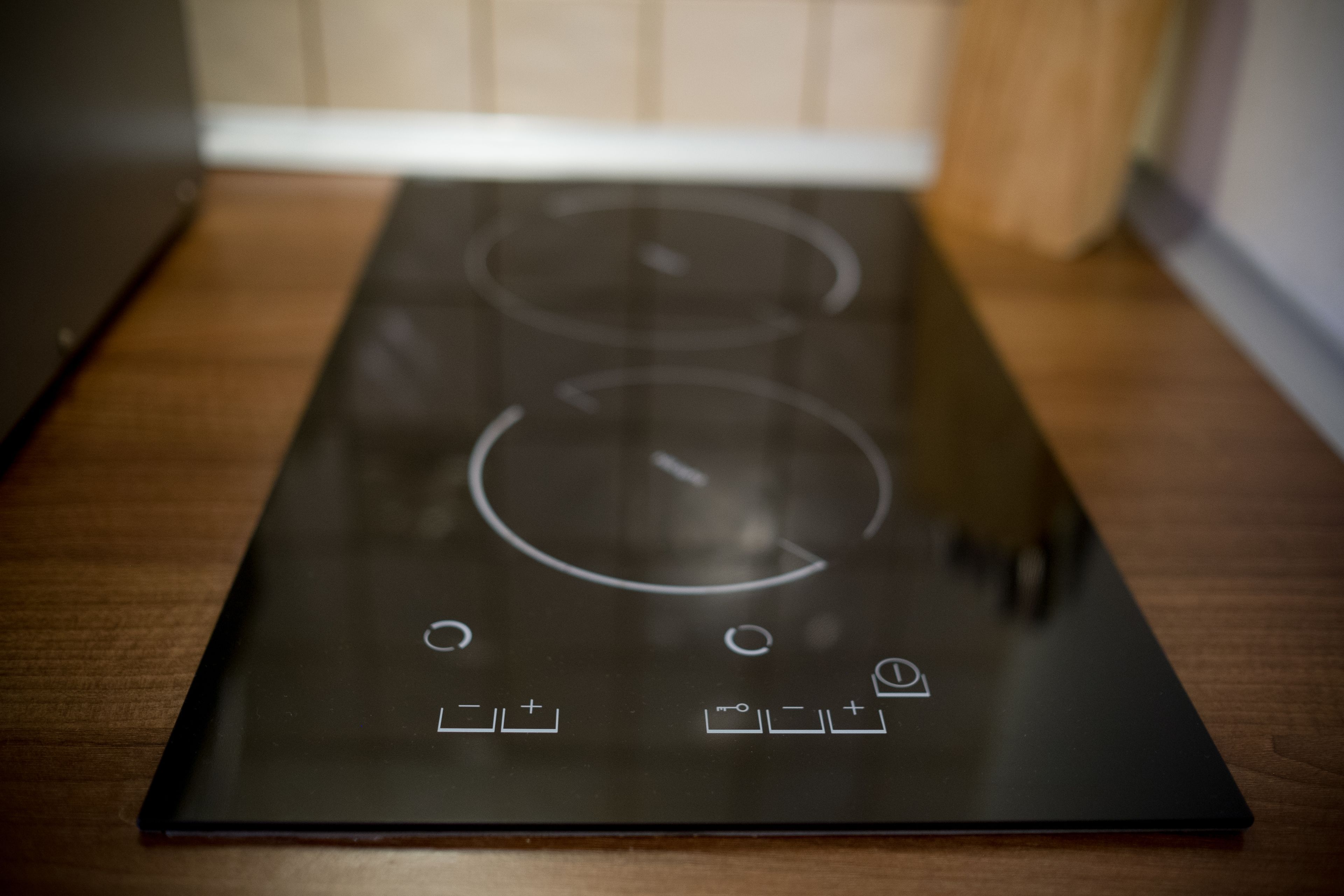 A kitchen with a black induction cooktop and a wooden countertop.