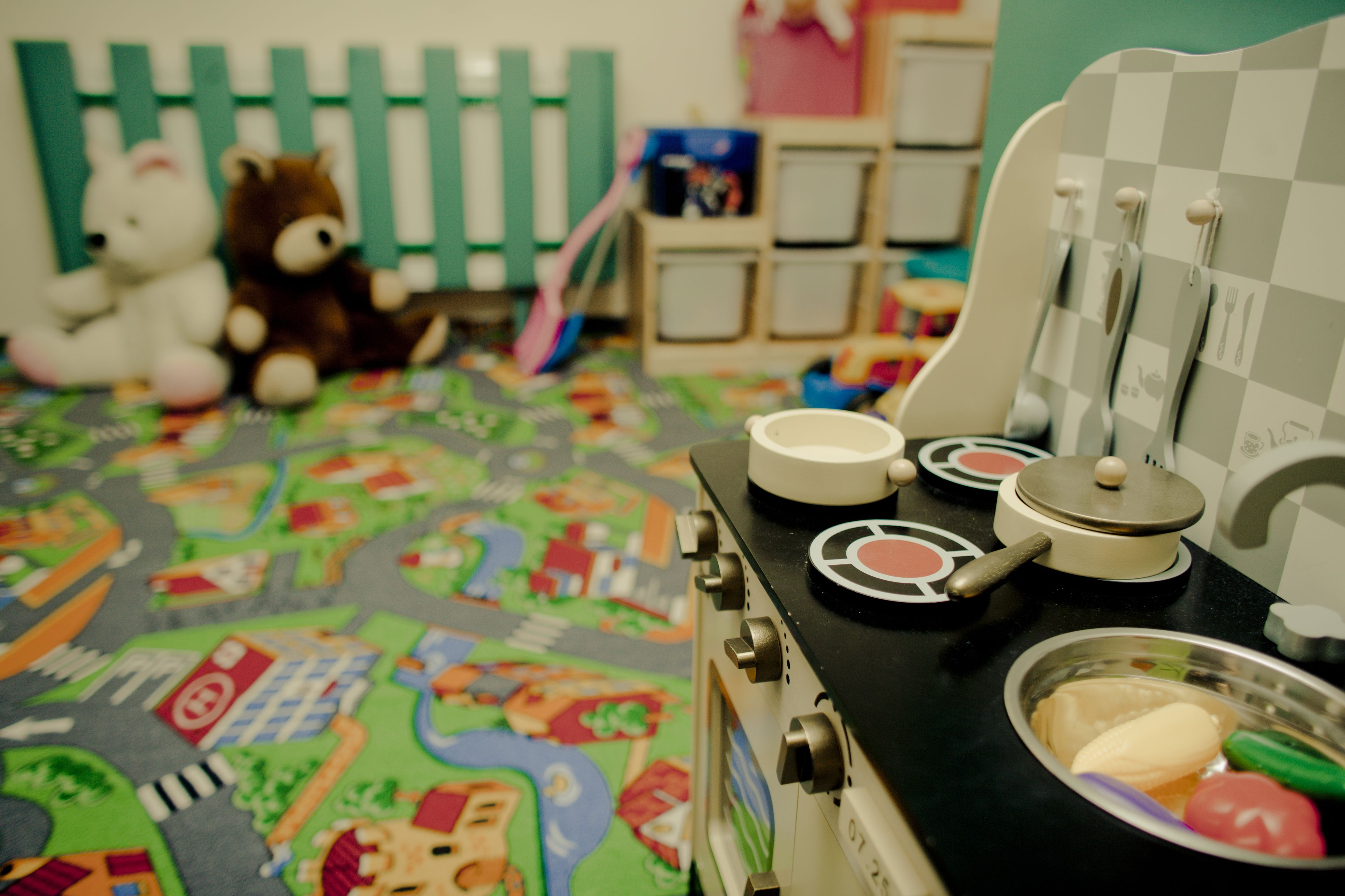 A children's play area with a toy stove, a toy kitchen set, and a colorful play mat.