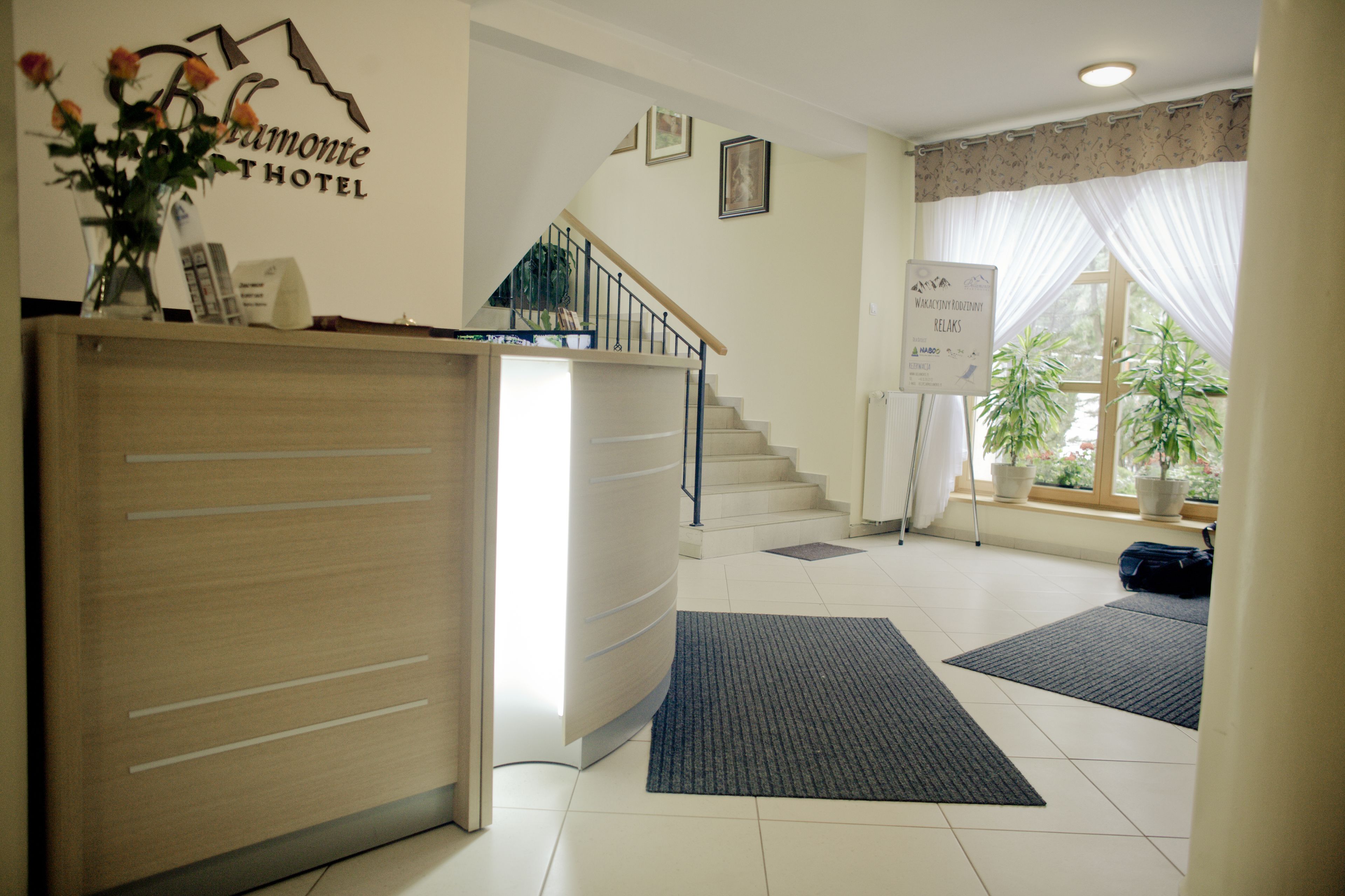 Ein Hotel-Empfangsbereich mit Empfangstresen, einer Treppe und einem Schild, das Entspannungsangebote kennzeichnet.